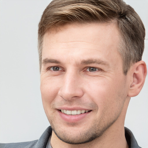 Joyful white young-adult male with short  brown hair and grey eyes