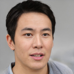 Joyful asian young-adult male with short  brown hair and brown eyes