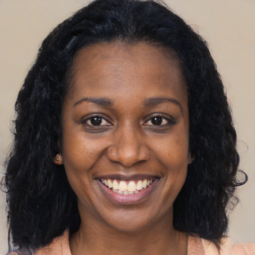 Joyful black young-adult female with long  brown hair and brown eyes
