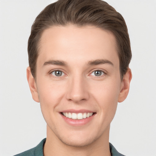 Joyful white young-adult male with short  brown hair and grey eyes