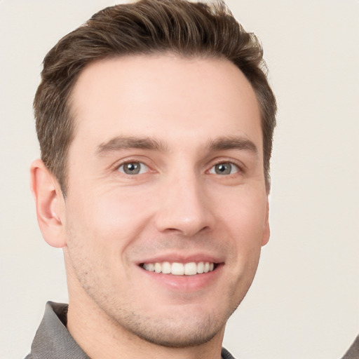 Joyful white young-adult male with short  brown hair and grey eyes