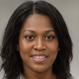 Joyful black young-adult female with long  brown hair and brown eyes