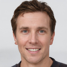 Joyful white young-adult male with short  brown hair and grey eyes