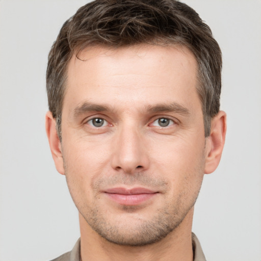 Joyful white young-adult male with short  brown hair and grey eyes