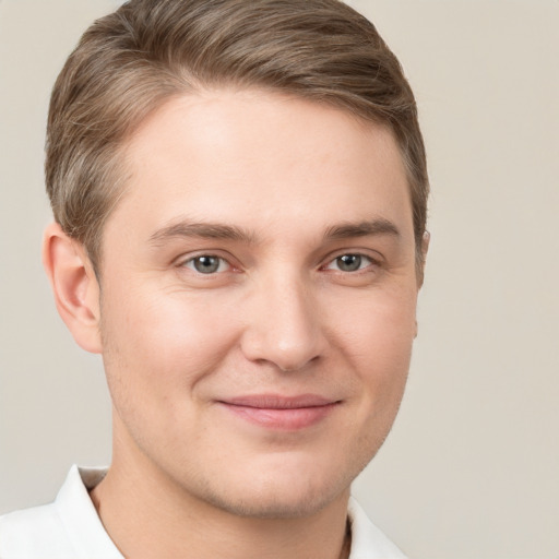 Joyful white young-adult male with short  brown hair and grey eyes