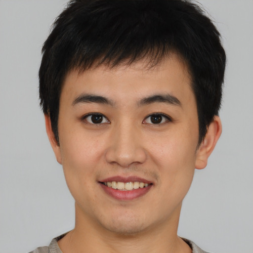 Joyful asian young-adult male with short  brown hair and brown eyes