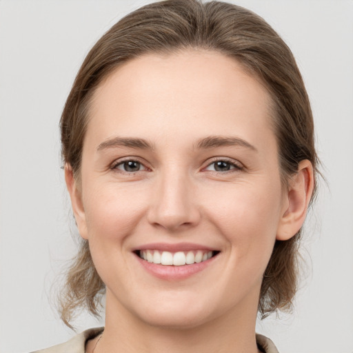 Joyful white young-adult female with medium  brown hair and grey eyes