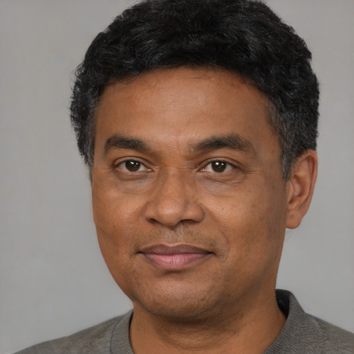 Joyful black adult male with short  black hair and brown eyes