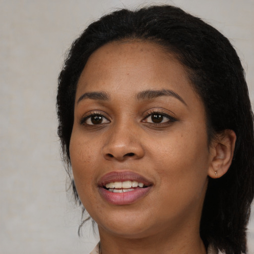 Joyful black young-adult female with long  black hair and brown eyes