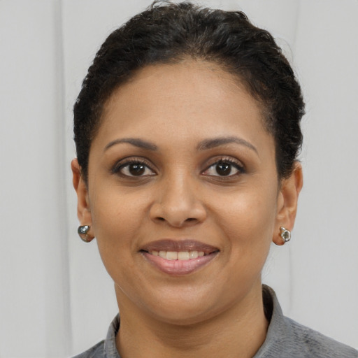 Joyful black young-adult female with short  brown hair and brown eyes