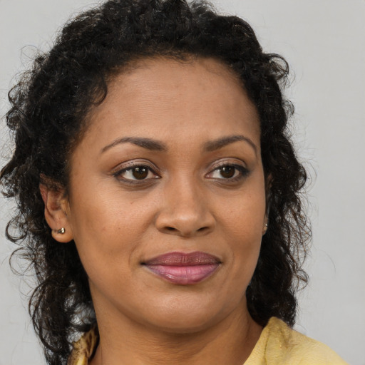 Joyful black young-adult female with long  brown hair and brown eyes