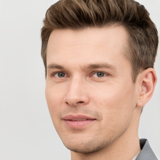 Joyful white young-adult male with short  brown hair and grey eyes