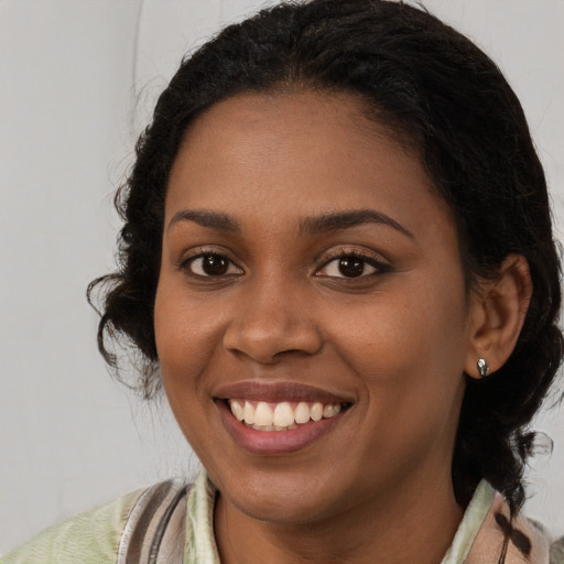 Joyful black young-adult female with long  brown hair and brown eyes