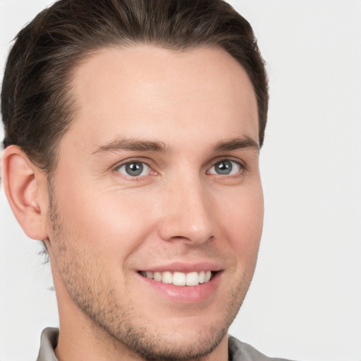 Joyful white young-adult male with short  brown hair and grey eyes