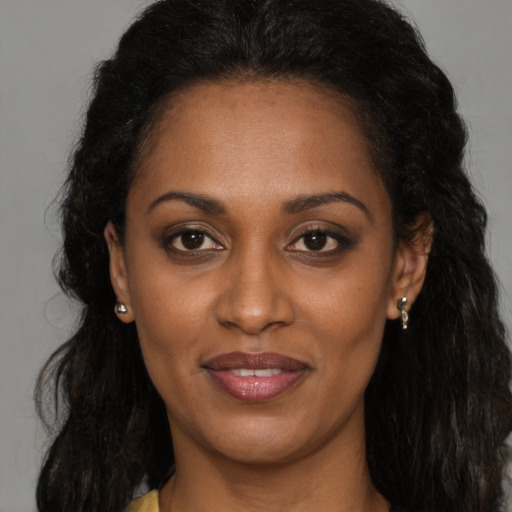 Joyful black young-adult female with long  brown hair and brown eyes