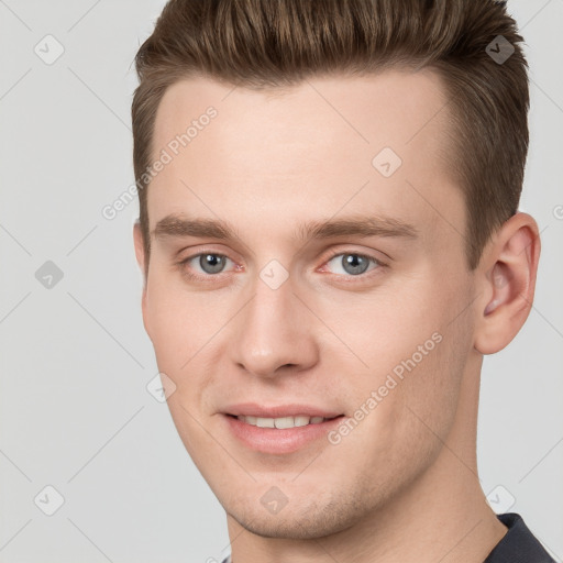 Joyful white young-adult male with short  brown hair and grey eyes