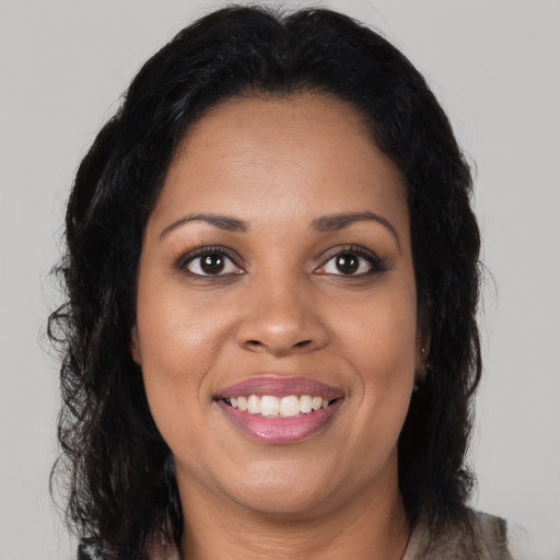 Joyful black young-adult female with long  brown hair and brown eyes