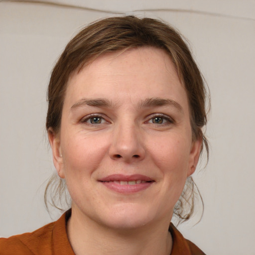 Joyful white young-adult female with medium  brown hair and grey eyes