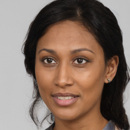 Joyful black young-adult female with long  brown hair and brown eyes