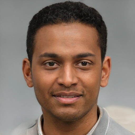 Joyful black young-adult male with short  brown hair and brown eyes