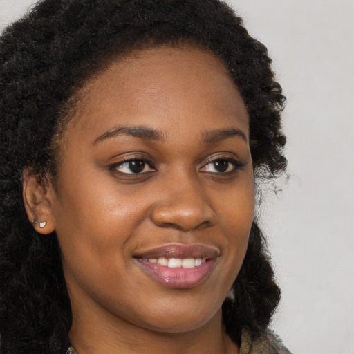 Joyful black young-adult female with long  brown hair and brown eyes