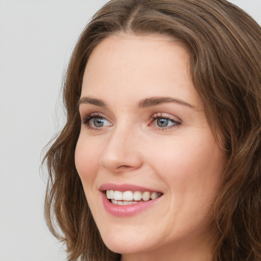 Joyful white young-adult female with long  brown hair and green eyes