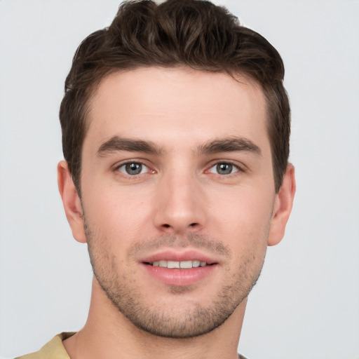 Joyful white young-adult male with short  brown hair and grey eyes