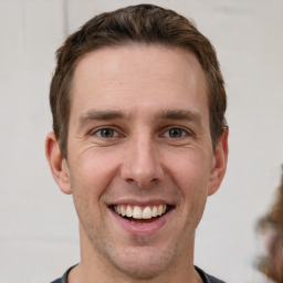 Joyful white young-adult male with short  brown hair and grey eyes