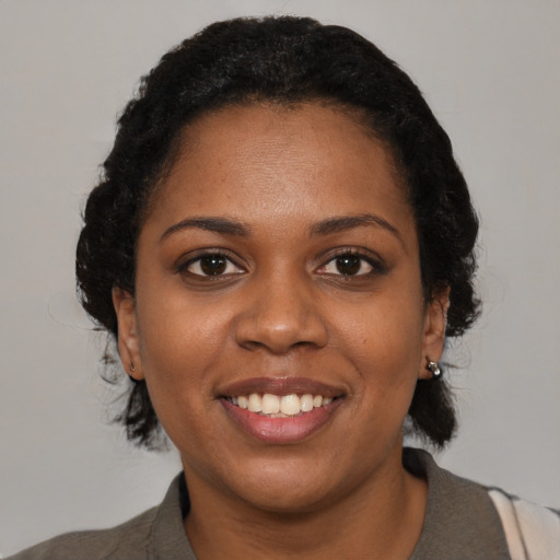 Joyful black young-adult female with short  black hair and brown eyes