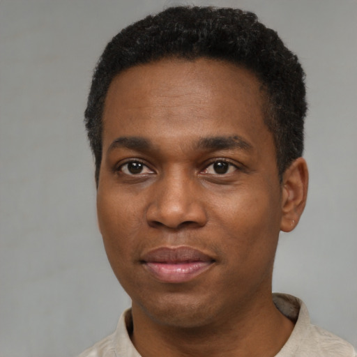 Joyful black young-adult male with short  black hair and brown eyes