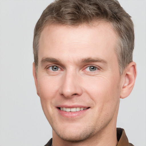 Joyful white young-adult male with short  brown hair and grey eyes