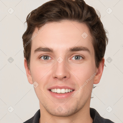 Joyful white young-adult male with short  brown hair and grey eyes