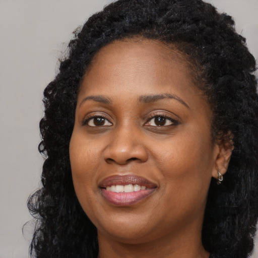 Joyful black young-adult female with long  black hair and brown eyes