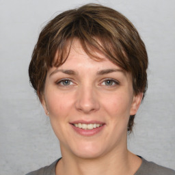 Joyful white young-adult female with medium  brown hair and grey eyes