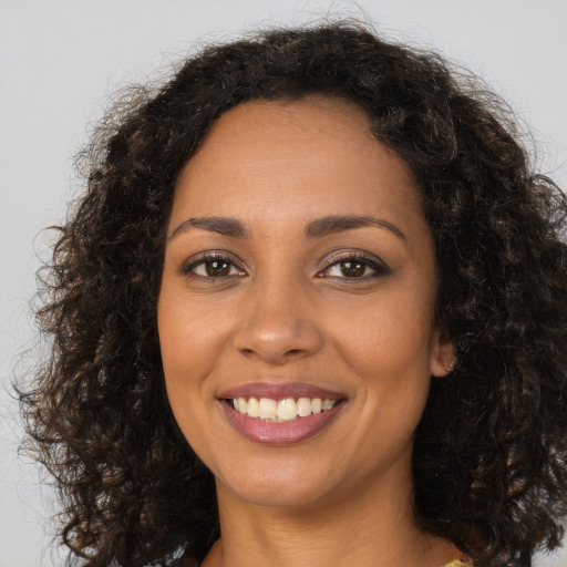 Joyful black young-adult female with long  brown hair and brown eyes