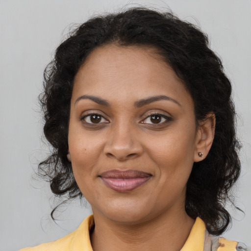 Joyful black adult female with long  brown hair and brown eyes