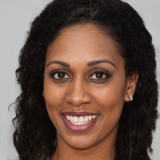 Joyful black young-adult female with long  brown hair and brown eyes