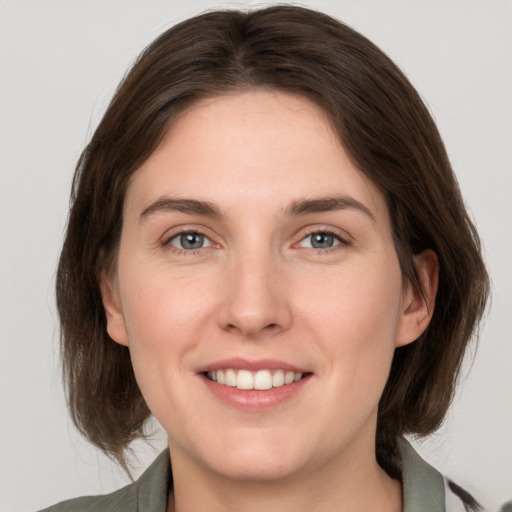 Joyful white young-adult female with medium  brown hair and grey eyes