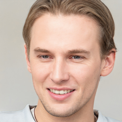 Joyful white young-adult male with short  brown hair and grey eyes