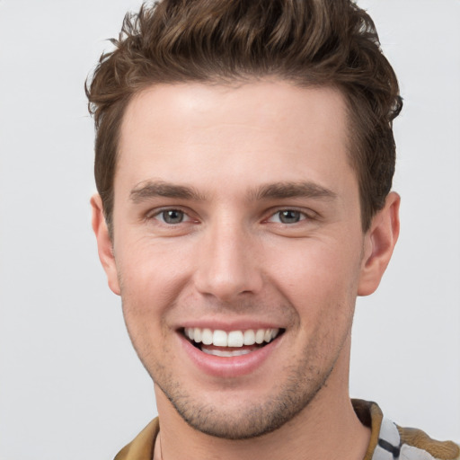 Joyful white young-adult male with short  brown hair and grey eyes