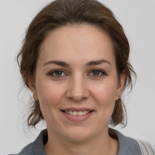 Joyful white young-adult female with medium  brown hair and grey eyes