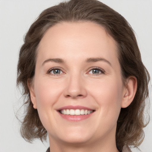 Joyful white young-adult female with medium  brown hair and grey eyes