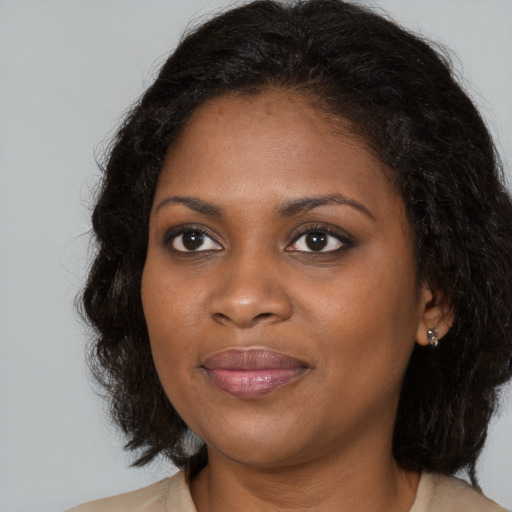 Joyful black young-adult female with long  brown hair and brown eyes