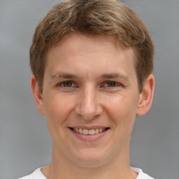 Joyful white young-adult male with short  brown hair and grey eyes