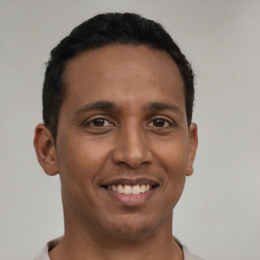 Joyful latino young-adult male with short  black hair and brown eyes