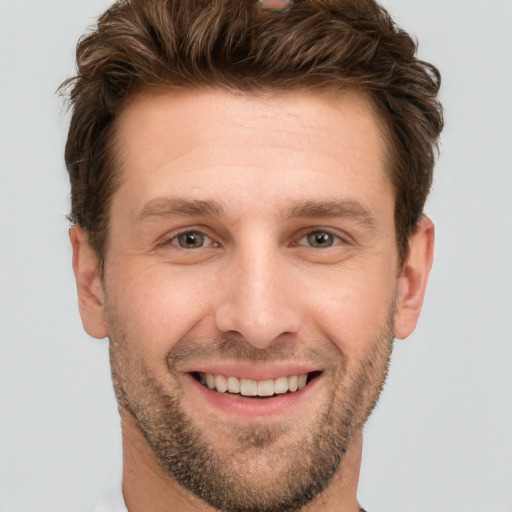 Joyful white young-adult male with short  brown hair and grey eyes