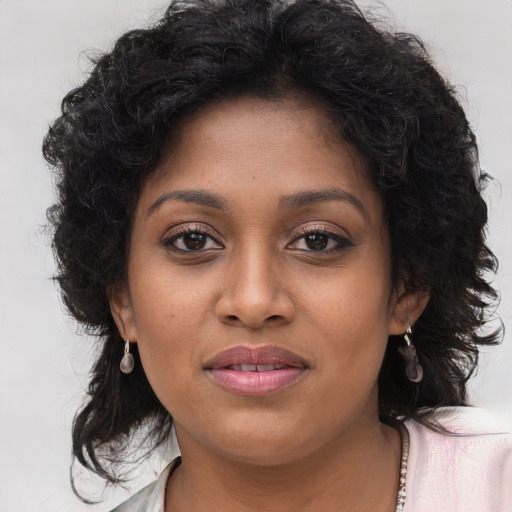 Joyful black young-adult female with long  brown hair and brown eyes