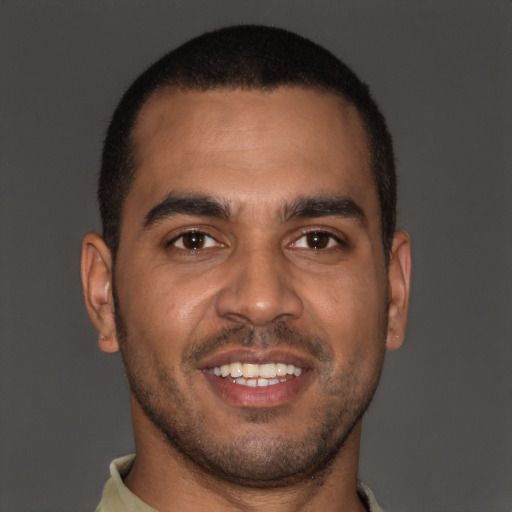 Joyful black young-adult male with short  brown hair and brown eyes