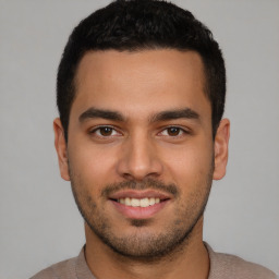 Joyful latino young-adult male with short  black hair and brown eyes