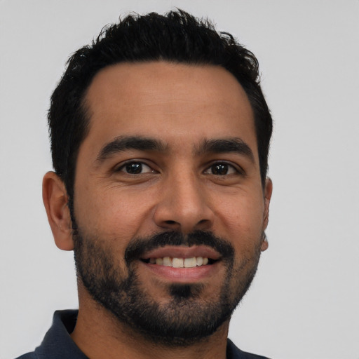 Joyful latino young-adult male with short  black hair and brown eyes